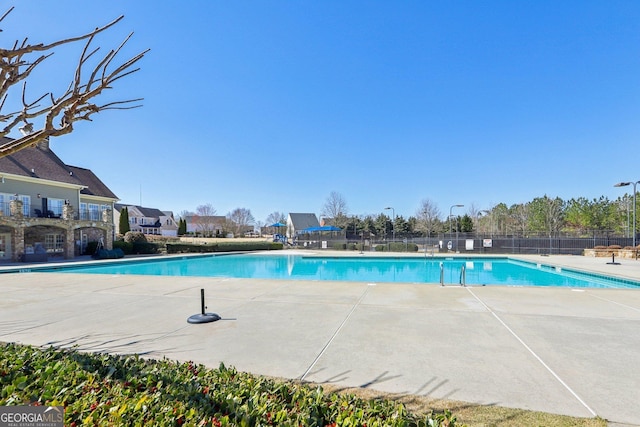 community pool with a patio area and fence