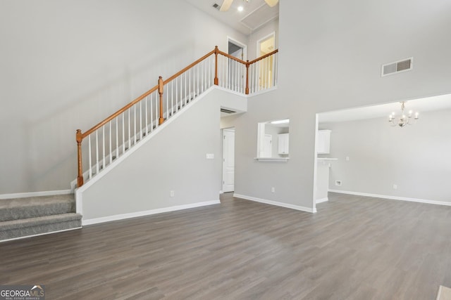 unfurnished living room with stairs, visible vents, baseboards, and wood finished floors