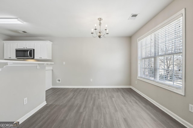 interior space with wood finished floors, visible vents, baseboards, and an inviting chandelier