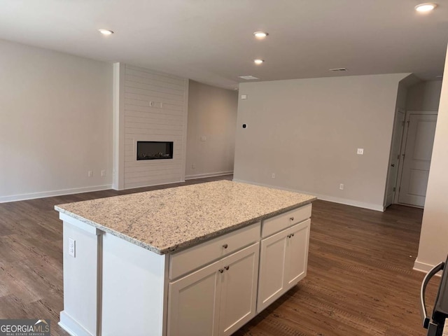 kitchen with recessed lighting, dark wood-type flooring, a fireplace, white cabinetry, and a center island