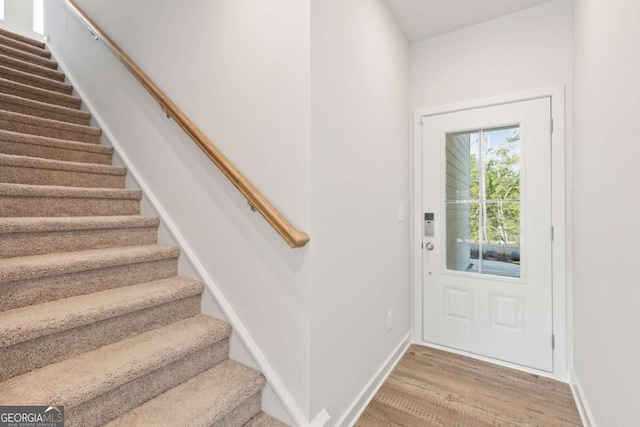 entryway featuring stairs, wood finished floors, and baseboards