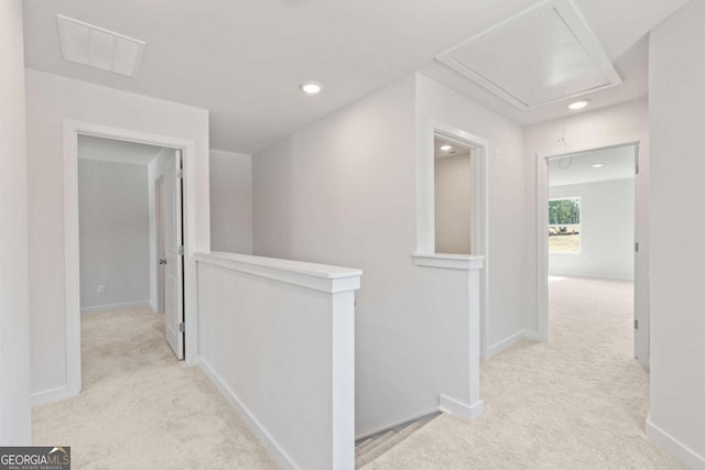 hallway with carpet floors, visible vents, attic access, an upstairs landing, and baseboards