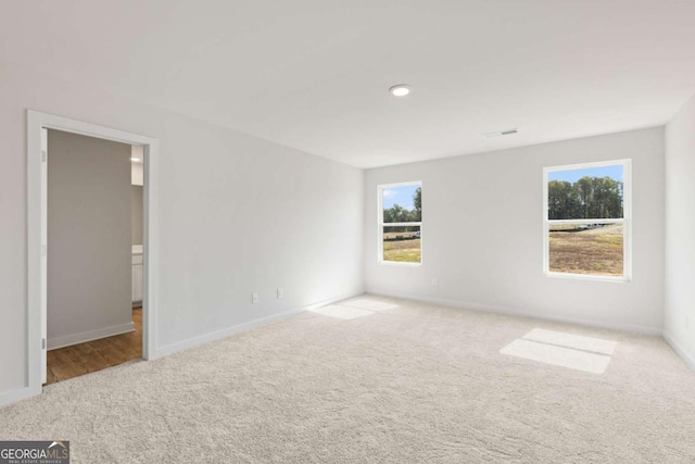 empty room featuring carpet flooring, visible vents, and baseboards