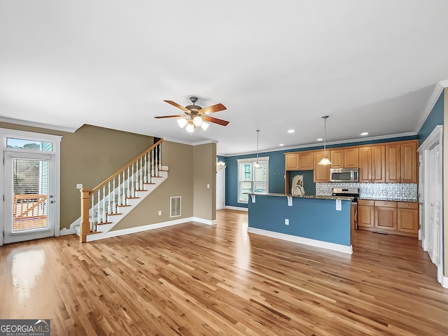 kitchen with crown molding, light wood finished floors, visible vents, appliances with stainless steel finishes, and open floor plan