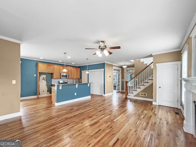 kitchen featuring stainless steel microwave, light wood-type flooring, backsplash, and visible vents