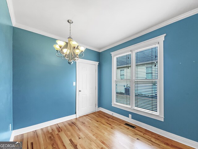 spare room featuring visible vents, baseboards, crown molding, light wood-style floors, and a notable chandelier