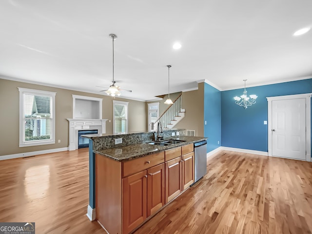 kitchen featuring ornamental molding, brown cabinets, stainless steel dishwasher, a fireplace, and a sink