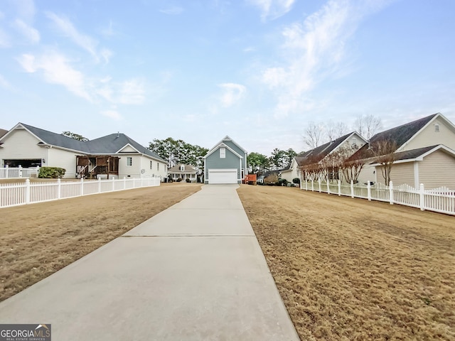 view of yard with a garage, a residential view, concrete driveway, and fence