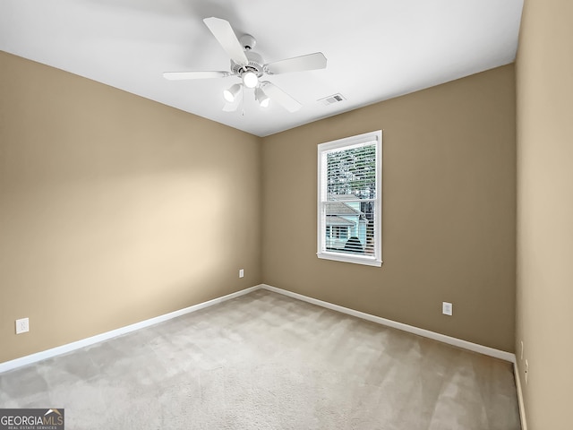 carpeted spare room featuring ceiling fan, visible vents, and baseboards