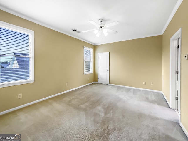 spare room with carpet flooring, a ceiling fan, baseboards, visible vents, and crown molding