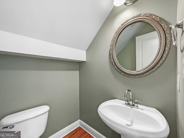 bathroom with baseboards, toilet, lofted ceiling, wood finished floors, and a sink