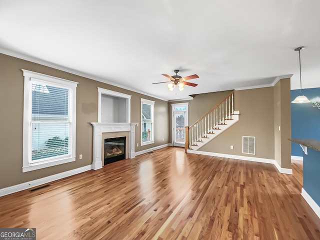 unfurnished living room with stairs, visible vents, and crown molding