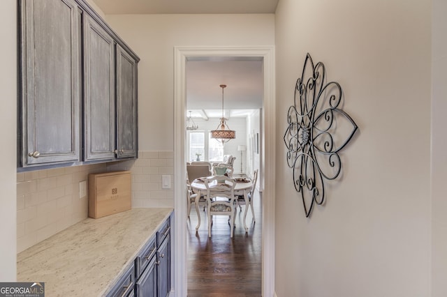 kitchen with light stone counters, dark wood finished floors, and backsplash