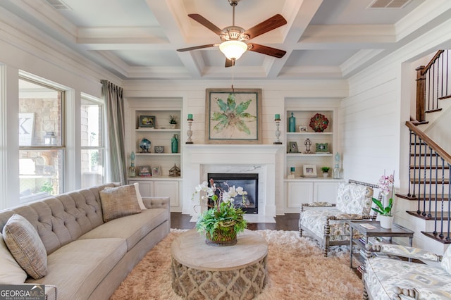 living area with coffered ceiling, stairs, a fireplace, and wood finished floors