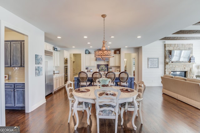 dining room with recessed lighting, dark wood-style flooring, and a stone fireplace