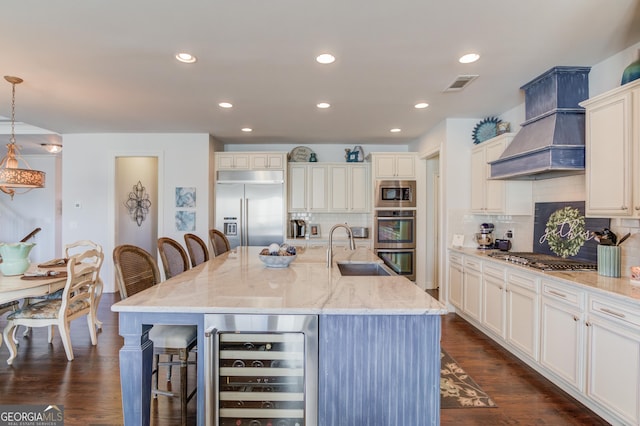 kitchen with beverage cooler, visible vents, a breakfast bar area, built in appliances, and a sink