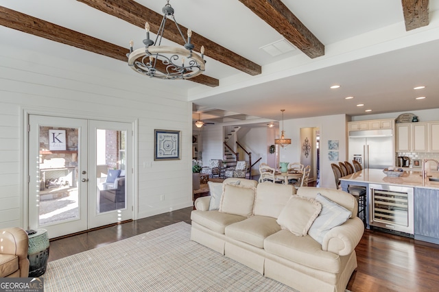 living room featuring dark wood-type flooring, beverage cooler, beamed ceiling, and stairs