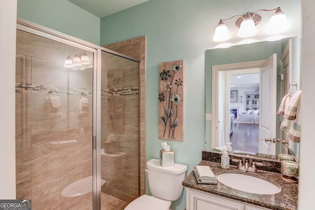 full bath with toilet, a shower stall, a fireplace, and vanity