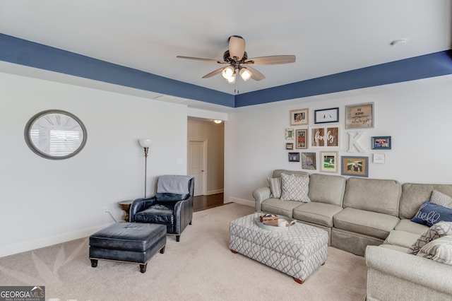 living area with a ceiling fan, light colored carpet, and baseboards