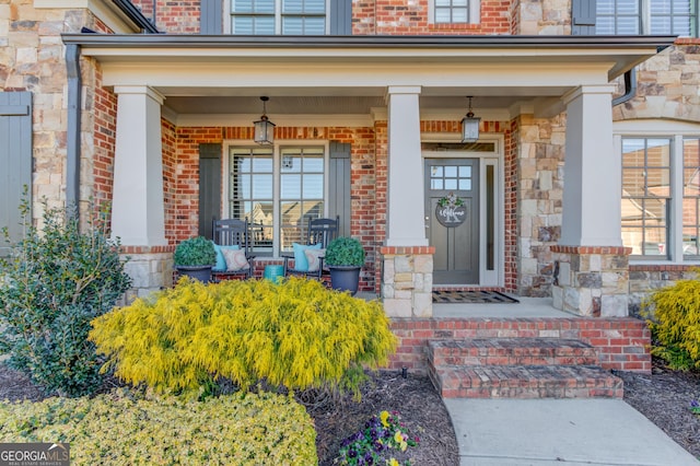 view of exterior entry with covered porch and brick siding