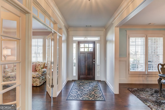 foyer entrance with a decorative wall, dark wood finished floors, visible vents, and crown molding