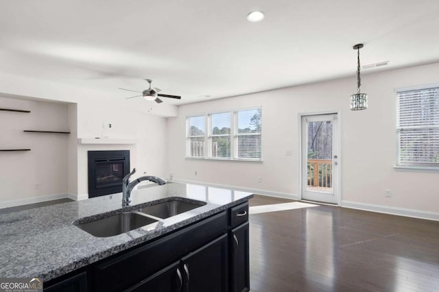 kitchen featuring plenty of natural light, visible vents, open floor plan, dark cabinetry, and a sink