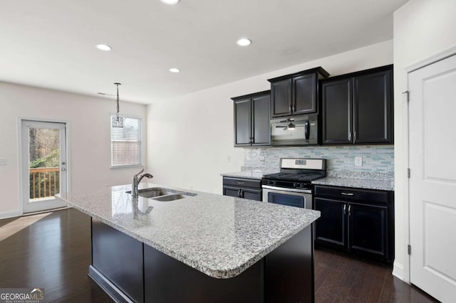 kitchen with dark wood finished floors, stainless steel range with gas stovetop, backsplash, black microwave, and a sink