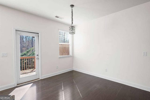 unfurnished dining area with baseboards, visible vents, and dark wood finished floors