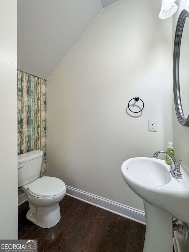 bathroom with lofted ceiling, baseboards, toilet, and wood finished floors