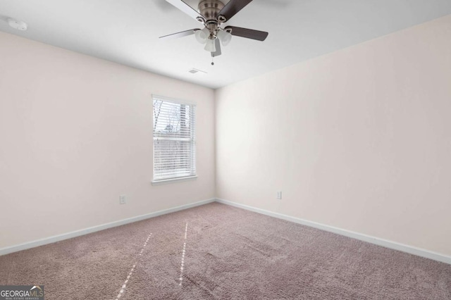 carpeted empty room featuring ceiling fan and baseboards