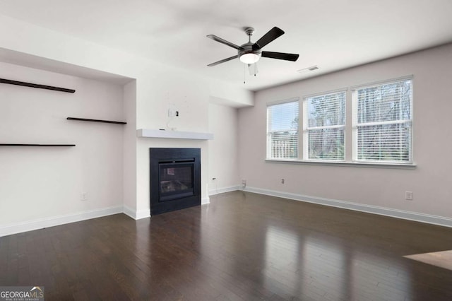 unfurnished living room featuring visible vents, baseboards, wood finished floors, and a glass covered fireplace