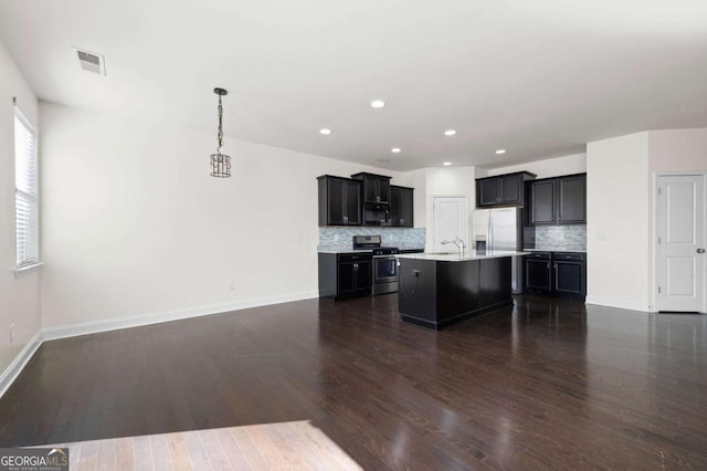 kitchen featuring dark wood-style floors, stainless steel appliances, light countertops, decorative backsplash, and open floor plan