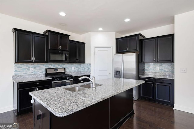 kitchen with dark wood-style floors, light stone countertops, stainless steel appliances, dark cabinetry, and a sink