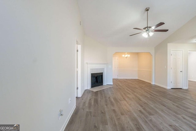 11139 Silver Aspen Ct, Hampton, GA 30228 - unfurnished living room featuring a ceiling fan, a chandelier, vaulted ceiling, a fireplace, and wood finished floors