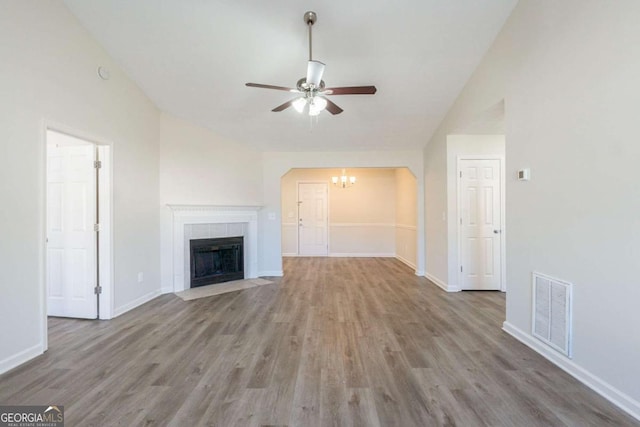 11139 Silver Aspen Ct, Hampton, GA 30228 - unfurnished living room with vaulted ceiling, a ceiling fan, wood finished floors, a chandelier, and a fireplace