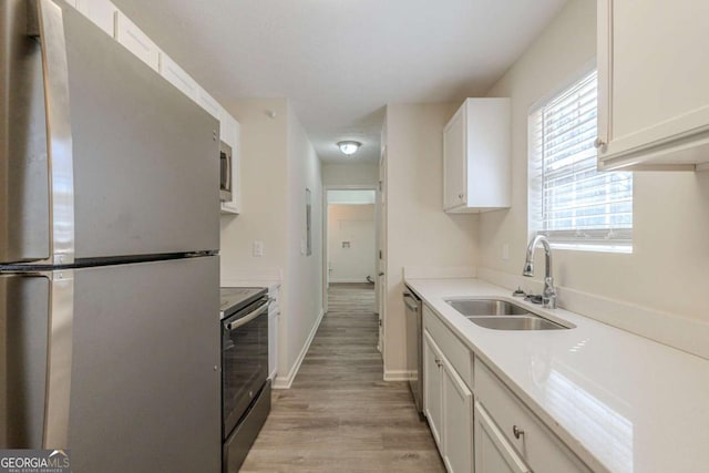 11139 Silver Aspen Ct, Hampton, GA 30228 - kitchen featuring appliances with stainless steel finishes, light wood-style flooring, white cabinetry, and light countertops