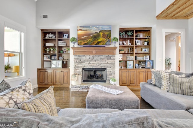 living area featuring visible vents, a stone fireplace, and wood finished floors