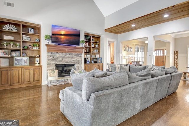 living room with dark wood finished floors, recessed lighting, visible vents, a stone fireplace, and high vaulted ceiling