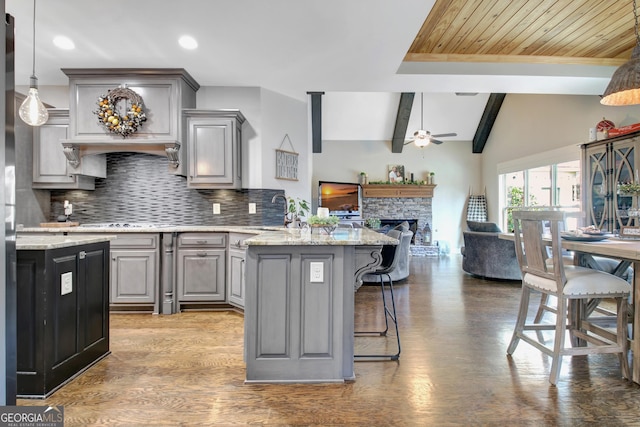 kitchen with decorative backsplash, lofted ceiling with beams, open floor plan, a peninsula, and gray cabinets