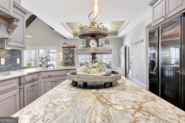 kitchen featuring stainless steel fridge with ice dispenser, wood ceiling, light stone counters, a tray ceiling, and backsplash