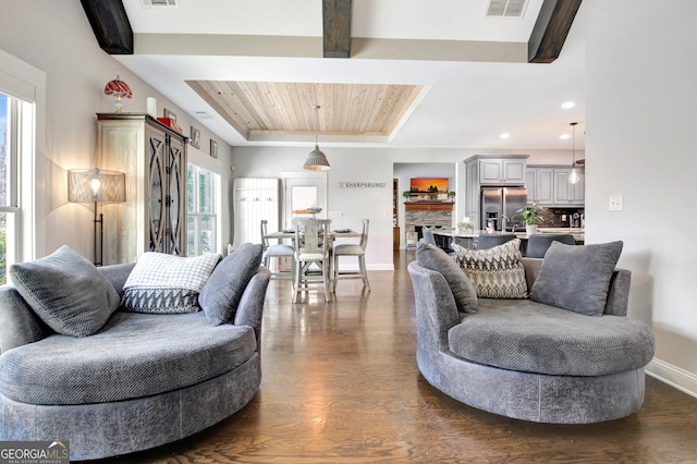 living area featuring visible vents, baseboards, dark wood finished floors, a raised ceiling, and beamed ceiling