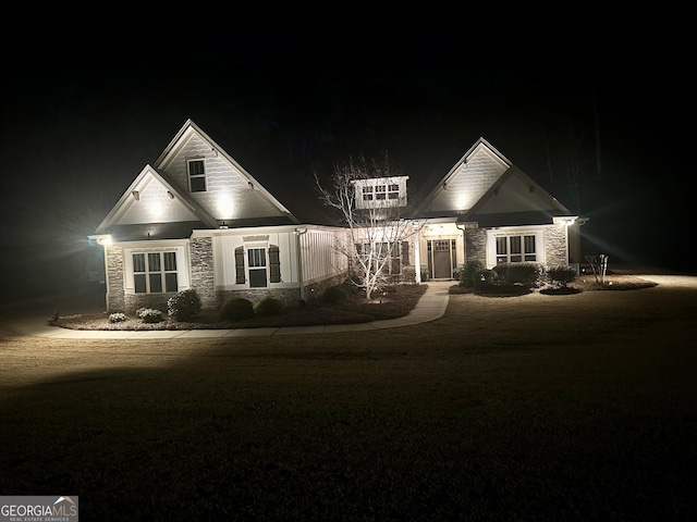 view of front of property featuring stone siding and a lawn