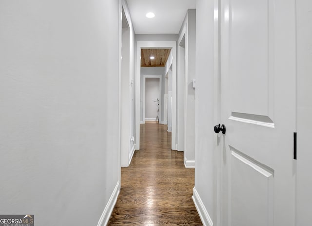 corridor with dark wood-type flooring, attic access, baseboards, and recessed lighting