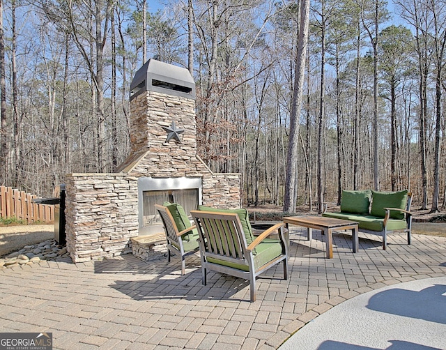 view of patio with an outdoor living space with a fireplace and fence