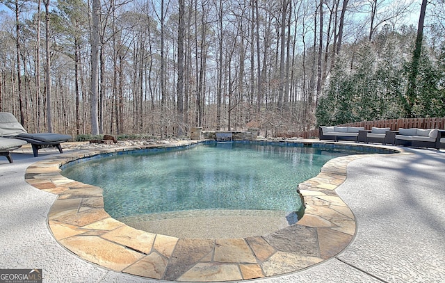 view of swimming pool featuring a forest view, a patio area, an outdoor living space, and a fenced in pool