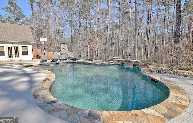 outdoor pool featuring a patio area, fence, and french doors