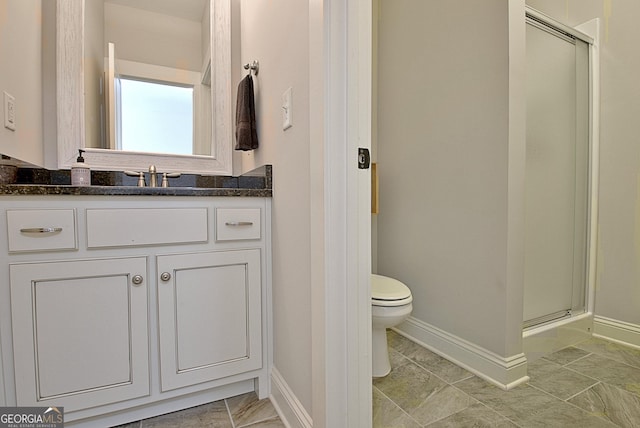 bathroom featuring a stall shower, vanity, toilet, and baseboards