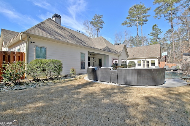 rear view of property featuring roof with shingles, fence, a chimney, and a swimming pool