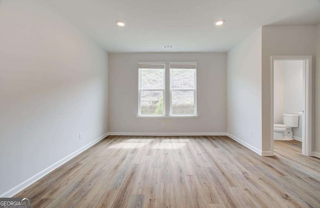 spare room with wood finished floors, baseboards, and recessed lighting