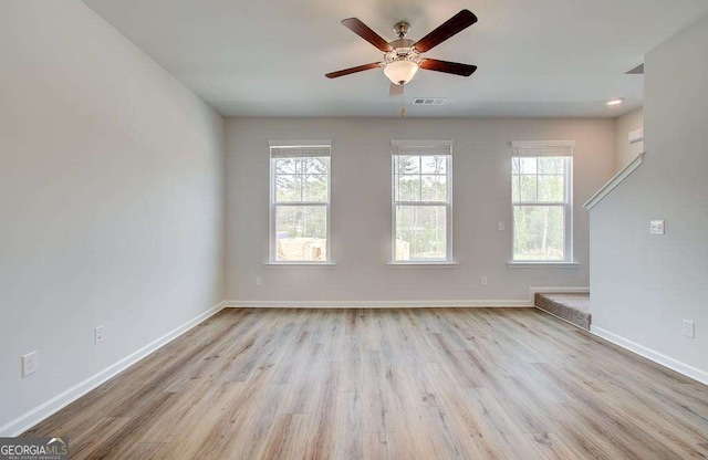 unfurnished living room with wood finished floors, baseboards, a ceiling fan, and visible vents